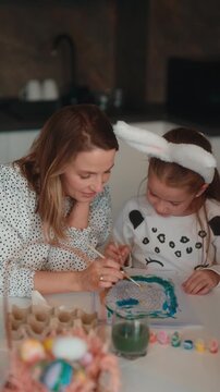 Happy Mother and Daughter Painting Easter Decorations Together at Home