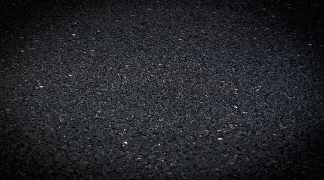 An asphalt road in a dark shades closeup texture.
