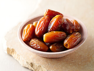 A bowl of dates on a stone surface indoor closeup