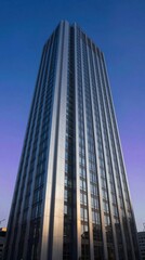 Tall building stands against twilight sky in urban area during evening hours with reflective windows