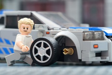 Obraz premium Tambov, Russian Federation - August 31, 2025 Lego Brian OConner minifigure changing wheel of his Nissan Skyline GT-R (R34) car. Lego Speed Champions