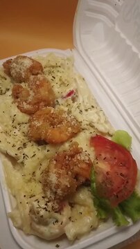 Delicious Crispy Shrimp with Creamy Pasta and a Slice of Fresh Tomato and Lettuce in Takeout Container, Close Up Vertical Video