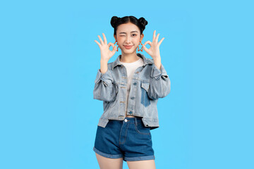Young woman winking and making an okay gesture against a vibrant background