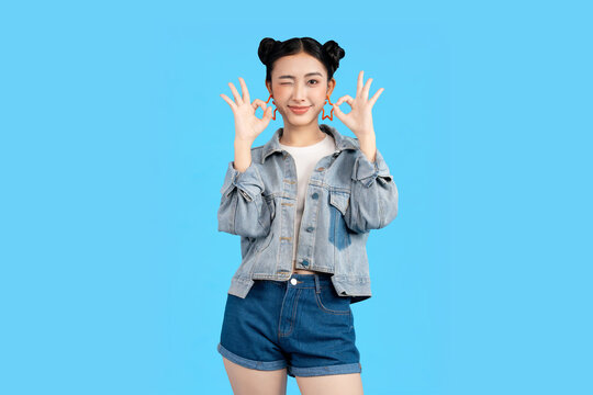 Young woman winking and making an okay gesture against a vibrant background