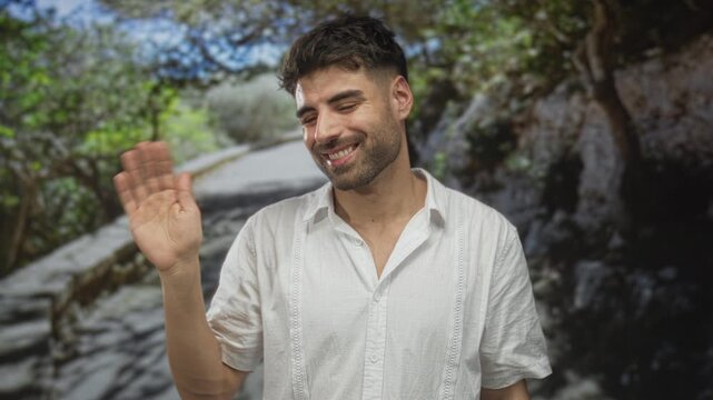 Young hispanic man points finger along a sunlit winding path in a green forest outdoors; welcome greeting.