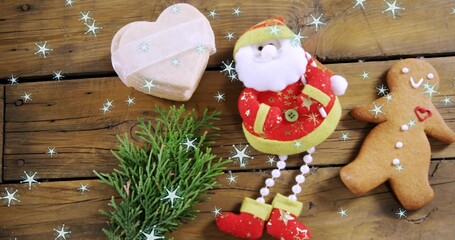 Displaying plush Santa ornament on rustic wood plank with cookie and heart box, copy space