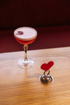 Red cocktail in a glass on a wooden table. Valentine's Day alcohol