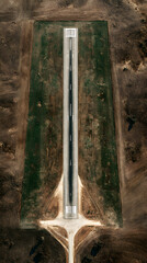 Short rural runway aerial view with approach markings and surrounding dry fields conveying isolation and restraint