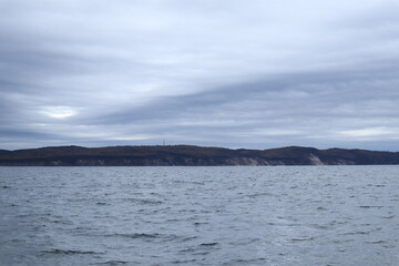 Sea with distant cliffs and cloudy sky
