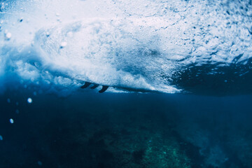 Underwater view of surfer rides wave with surfboard, deep blue ocean energy and extreme water sports concept.