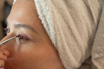 Woman blending eyeshadow with a makeup brush on her face.
Beauty and skincare routine concept. Professional makeup application, cosmetics, self-care, and personal grooming. Close-up portrait.