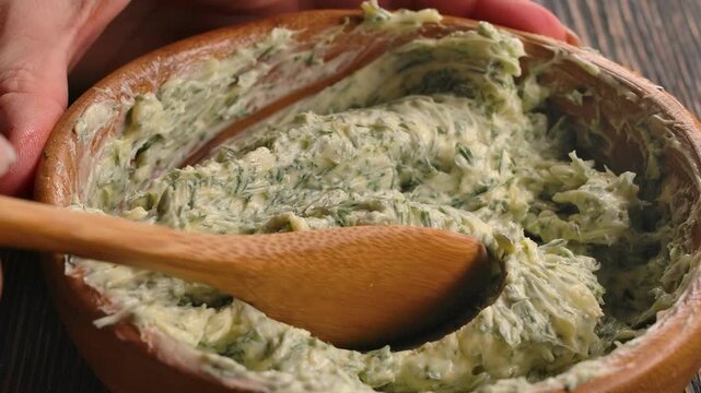 A wooden spoon scoops up smooth, golden garlic butter sauce. Perfect clip for cooking, recipes, food blogs, and culinary content