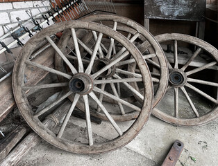 Wooden Wheels Stacked in a Storage Area Near a Farming Tool Shed During the Day