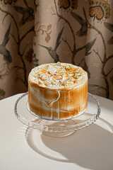 Meringue cake with toasted creamy peaks and citrus zest served on glass stand in restaurant style