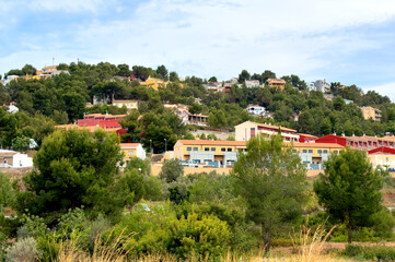 Obraz premium Colourful Houses on mountainside on Sunset. Residential buildings in town at Valencia mountains. Panoramic of Gilet, Spain city. Home on mountain. Village with colourful house in rural. Hoses in Town