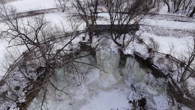 Hight aerial nosedive shot of Frozen waterfall and bridge in Wisconsin park in winter.