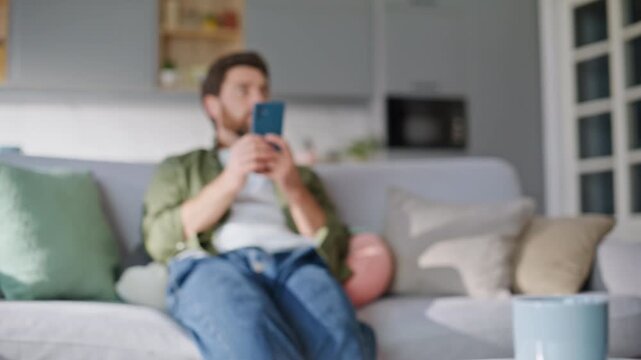 Preteen daughter vacuuming floor father sitting home couch with smartphone. 