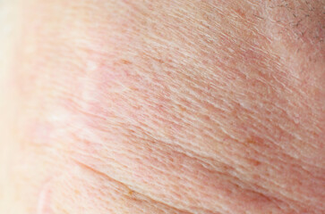 Naklejka premium Extreme close-up of aged human skin texture with fine wrinkles and subtle discoloration