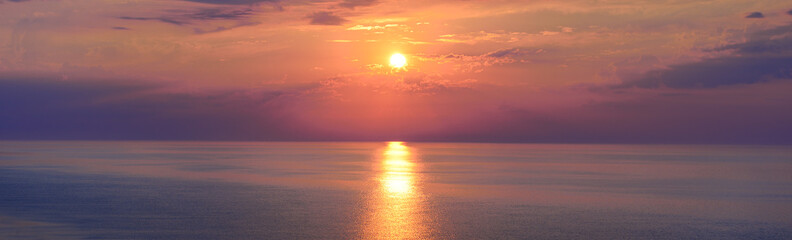 Ocean sunset with dramatic sky and glowing horizon in warm pastel tones, symbol of tranquility
