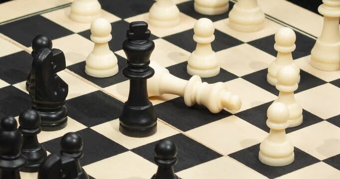 A Zoom out of a black king chess piece check mate over a chess board in a victory concept