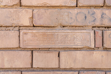 Modern mud-brick in a wall which was inscribed that mentions the name of Saddam Hussein as the president and protector of the great Iraq.
