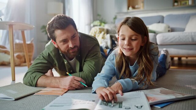 Father helping daughter studying school lesson lying apartment floor closeup.