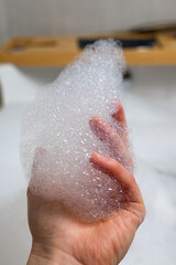 Fototapeta premium Detailed view of fingertips cradling airy bubbles in calming bath setting