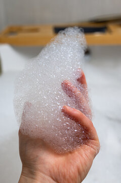 Detailed view of fingertips cradling airy bubbles in calming bath setting