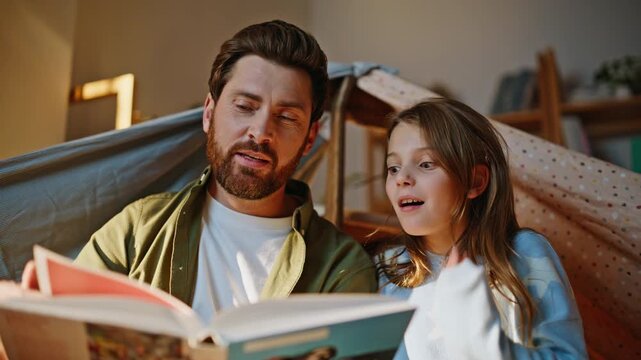 Father child enjoy storytelling blanket fort closeup. Patient dad reading