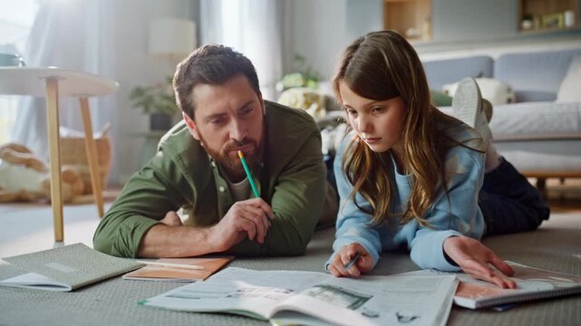 Father daughter solving school tasks looking textbooks lying floor closeup. 