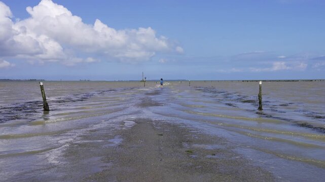 Boy walking into the water of the flooded street Passage du Gois.
