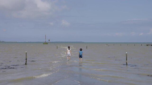 Children walking into the water of the flooded street Passage du Gois.