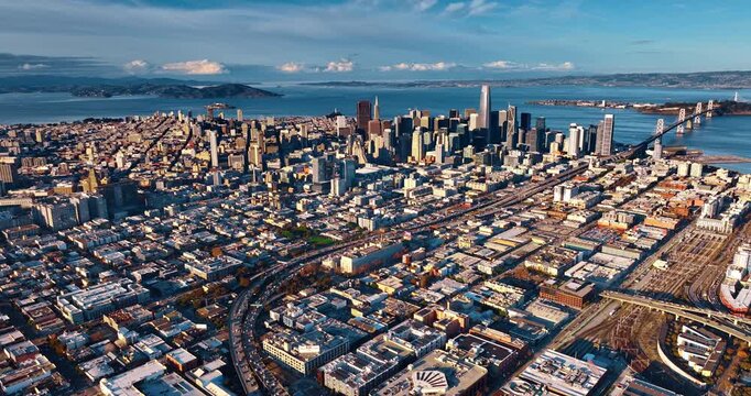 Sunny cityscape of modern San Francisco, California, USA. Highways leading to the Oakland Bay Bridge are filled with multiple cars. Aerial view.