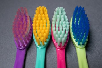 Colorful toothbrushes arranged in a row on a dark background showing different bristle shapes and colors