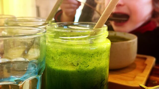 Child eating green vegetable soup