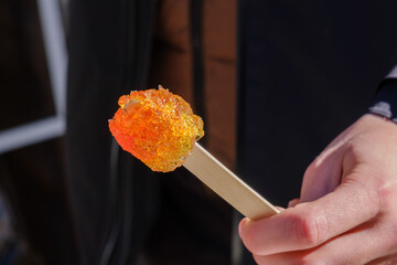 Hand holding a fresh maple taffy stick in winter