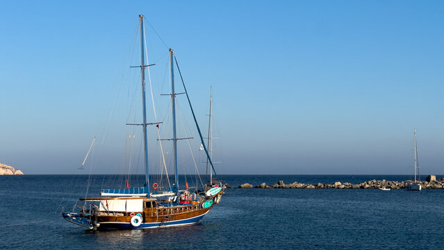 Traditional wooden gulet sailboat anchored in the calm deep blue waters of the Aegean Sea at Knidos harbor, Turkey
