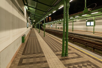 Empty Vienna metro platform at night with green columns and canopy. Vienna, Austria