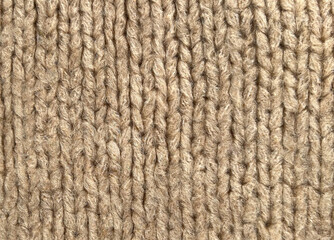Close-up of beige knitted fabric with vertical knit pattern. Soft wool textile texture in warm natural tones. Cozy sweater background suitable for winter fashion, handmade design, minimal backgrounds 