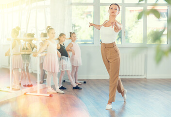 Fototapeta premium Children visitors to choreographic classes, observe professional rendering of dance elements, performances middle-aged woman couch. Aesthetic hobby for fans of active lifestyle