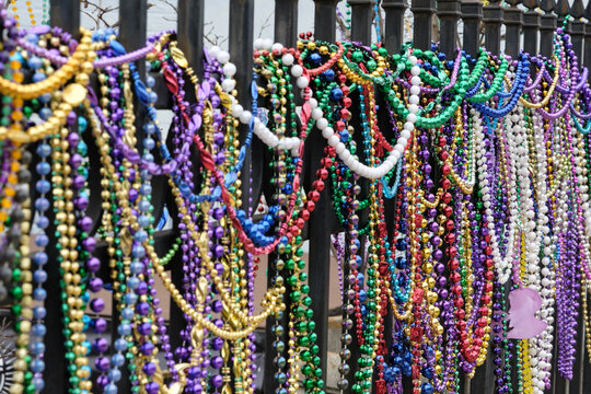 Closeup of many multicolored mardi gras beads hanging on a fence