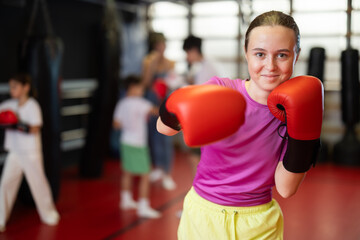 Obraz premium Teenage girl in red boxing gloves at training in the gym. Portrait of a boxing teenager. Muay Thai training for children