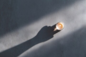 minimalist home decor, tranquil flat lay with a candle casting a raised fist shadow on the wall, against a neutral gray background, in soft natural light