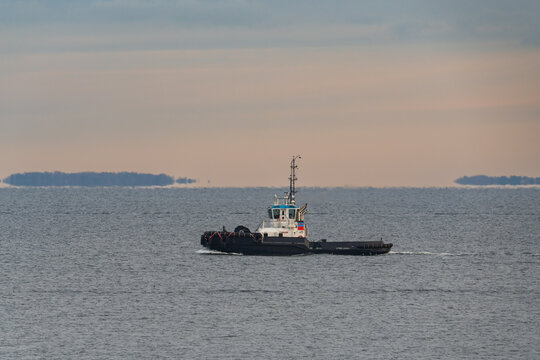 Professional tugboat vessel sailing on the calm waters of the Baltic Sea during a grey overcast day in northern Europe