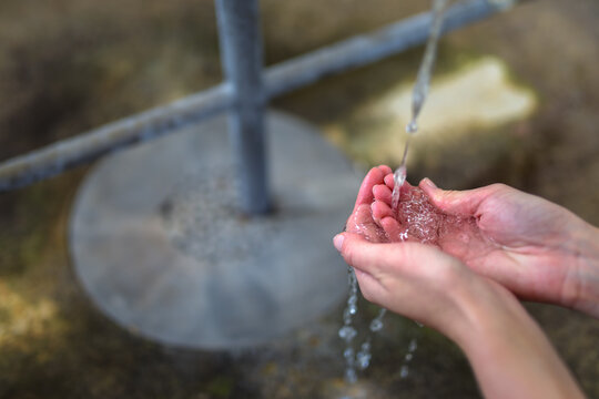 Close-up of hands catching fresh mineral water from a pipe at the Gallas spring in Teplice nad Bečvou spa.