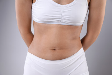 Woman in underwear after weight loss on grey background, closeup