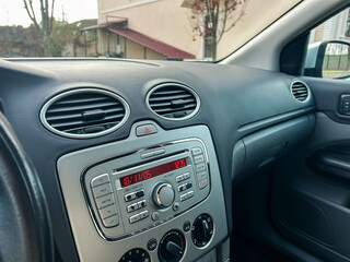 Obraz premium Dashboard of a car showing time and radio controls in a parked vehicle near a building during daylight hours
