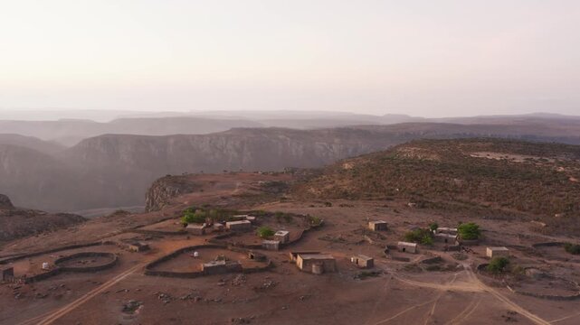 Aerial view of a remote village nestled in the mountains of Socotra, Yemen, showcasing traditional architecture and a majestic mountainous backdrop