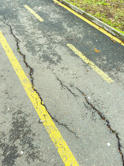 Fototapeta premium Cracks appear in yellow lines on asphalt road marking during daylight in a suburban area