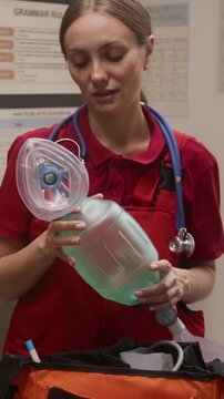 Vertical shot of smiling young female doctor showing ventilation mask to group of kids while giving interactive presentation on career day in school